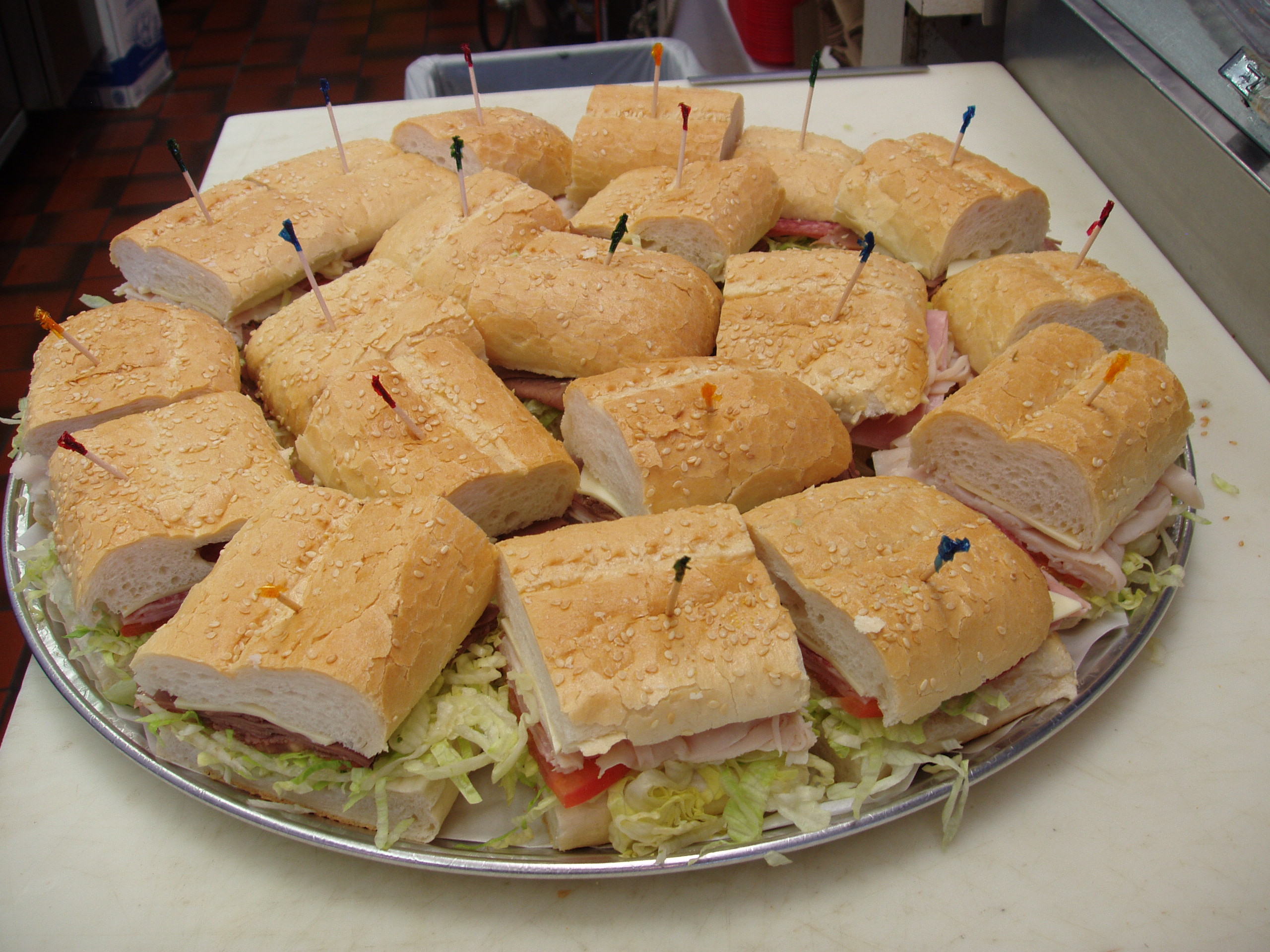 A clearer Submarine City party tray filled with sandwich pieces for group catering.