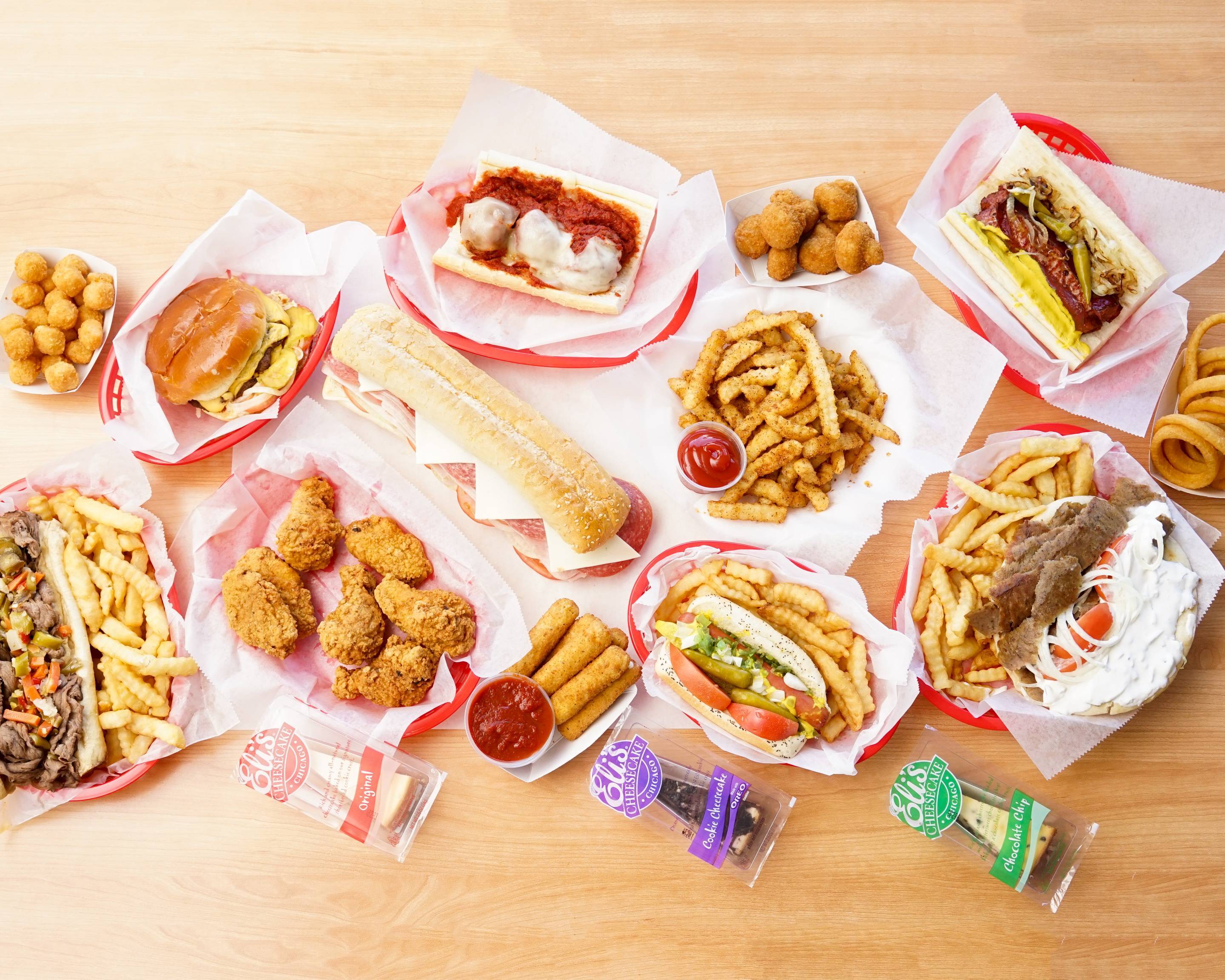 A spread of Submarine City food including sandwiches, fries, chicken, hot dogs, and sides.